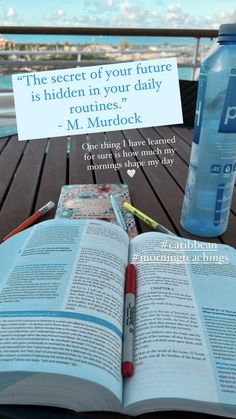 an open book sitting on top of a wooden table next to a water bottle