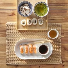 an overhead view of sushi and chopsticks with dipping sauce on the side