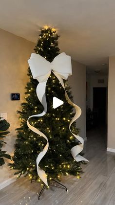 a christmas tree decorated with white ribbon and lights