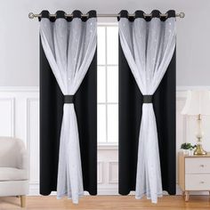 two black and white curtains hanging on the side of a window in a living room