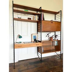 a wooden desk topped with a shelf filled with lots of books and other items next to a white wall