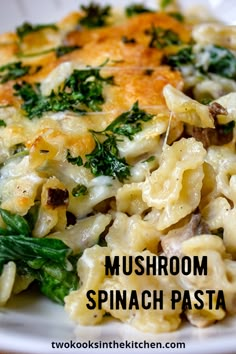 a white plate topped with pasta covered in cheese and spinach toppings on top of a wooden table