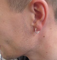 a close up of a man with a nose ring on his ear and wearing a black shirt