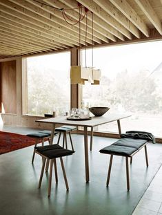 a dining room table and chairs in front of a large window with an area rug on the floor