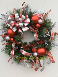 a christmas wreath hanging on the side of a building with red and silver ornaments around it