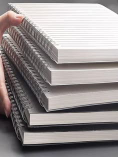 a stack of notebooks being held by a person's hand on a table