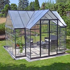 a small glass house sitting on top of a lush green field