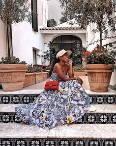 a woman is sitting on the steps talking on her cell phone while wearing a blue and white dress