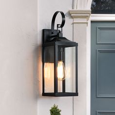 an outdoor light on the side of a building with a potted plant next to it