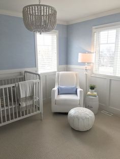 a baby's room with blue walls, white furniture and a chandelier