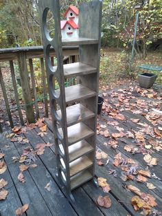 a book shelf sitting on top of a wooden deck next to leaves and a birdhouse