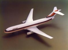 the model airplane is white and orange with stripes on it's tail, sitting on a gray surface