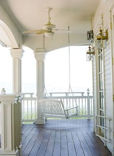 a porch with a swing chair and ceiling fan