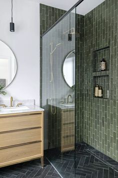 a bathroom with green tiles on the walls and floor, along with a wooden cabinet