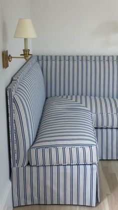 a blue and white striped couch sitting next to a lamp