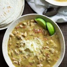 a white bowl filled with soup next to two tortillas