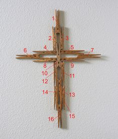 a wooden cross hanging on the side of a white wall with numbers and measurements below it