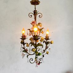 a chandelier hanging from the ceiling with flowers and leaves on it's arms