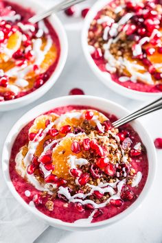 three bowls filled with fruit and yogurt on top of a white tablecloth