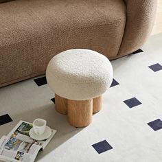 a white ottoman sitting on top of a floor next to a brown couch and coffee table