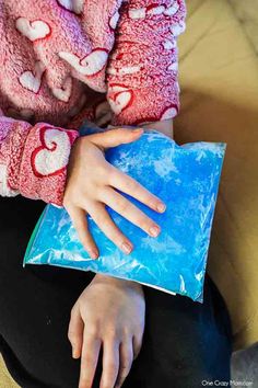 a woman sitting on a couch holding a blue bag with hearts painted on the side