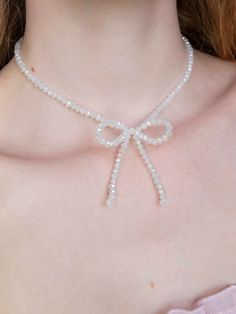 a close up of a woman wearing a white necklace with pearls on it's neck