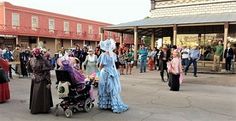 many people are walking around in costumes and dresses on the street while others walk by