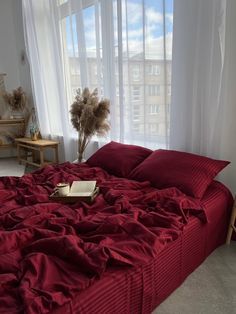 a bed with red sheets and pillows in a room