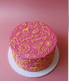 a pink cake with gold lettering on it