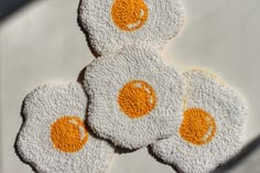 four fried eggs on top of each other with orange and white crochet designs