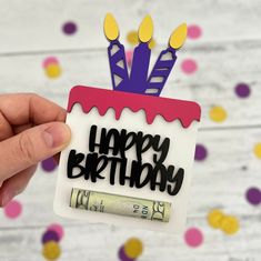 a person holding up a birthday card with candles on it and money in front of them