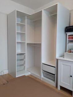 an empty bedroom with white closets and drawers on the wall, next to a bed