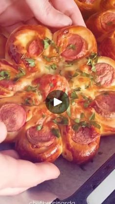 two hands reaching for a pizza with pepperoni and sausages on it in front of other hands