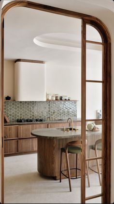 a kitchen with an island in the middle and wooden cabinets on both sides, along with two stools