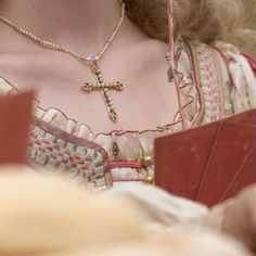 a close up of a woman wearing a necklace with a cross on it