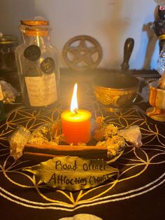 a lit candle sitting on top of a table next to some bottles and cookies in front of it