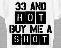 a white t - shirt with the words 33 and hot buy me a shot on it