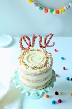 a birthday cake with sprinkles and the word one on top is sitting on a plate