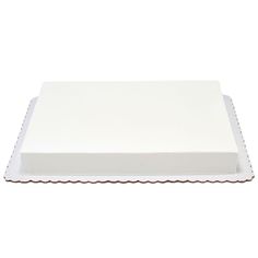 a white square cake with scalloped edges on a white surface, isolated against a white background