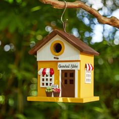 a yellow birdhouse hanging from a tree branch