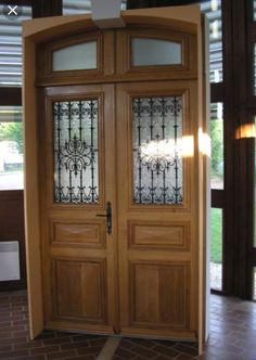 two wooden doors with glass panels on the top and bottom, in front of a brick floor