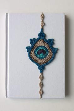 a book with an embroidered eye on the front and back cover, sitting on a white surface