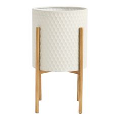 a white planter with wooden legs on a white background, it has a geometric pattern