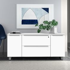 a blue chair sitting next to a white cabinet with a painting on it's wall