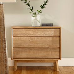 a wooden dresser sitting next to a lamp on top of a hard wood floor