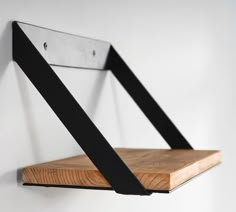 a wooden shelf with metal straps hanging from it's sides on a white wall