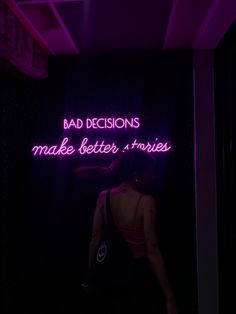 a woman standing in front of a neon sign that says bad decisions make better, stories