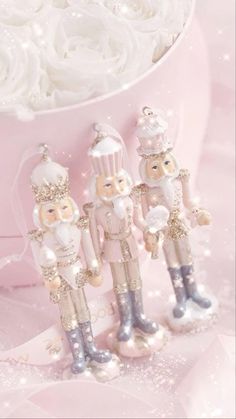 three small figurines in the shape of nutcrackers on a pink background