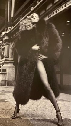 a woman in a fur coat is posing for the camera with her legs spread out