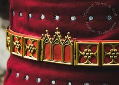 a red velvet belt with gold trimmings and an ornate design on the waist